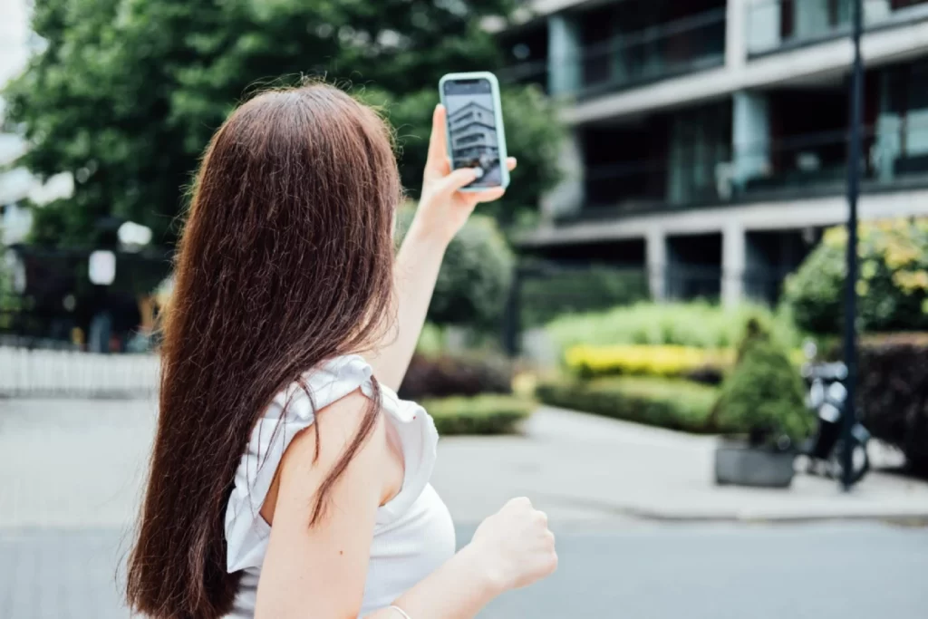 Žena pořizuje fotku nemovitosti mobilním telefonem